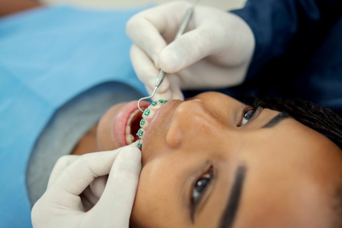 Orthodontist checking teen girl's braces