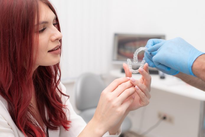 Orthodontist showing young woman Invisalign aligners