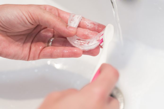 Invisalign retainers being brushed in sink