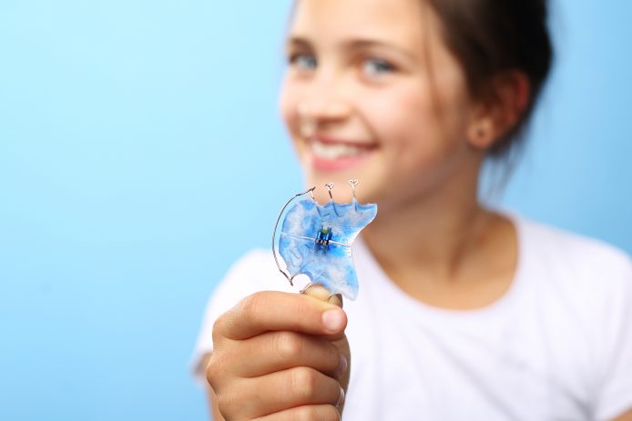Girl holding out a blue retainer
