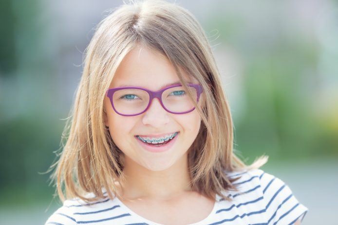 Young girl with purple glassess and blue traditional braces