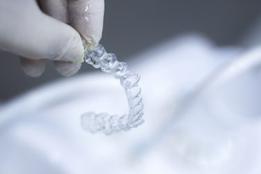 Hand with rubber glove holding clear aligners