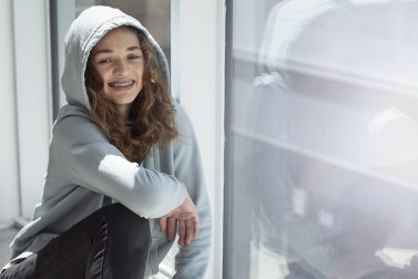 Teenage girl in sweatshirt smiling with braces