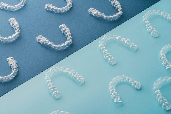 Many different clear aligners on blue background