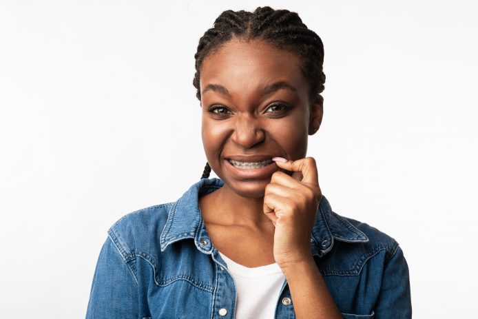 Teenage girl wincing and touching braces