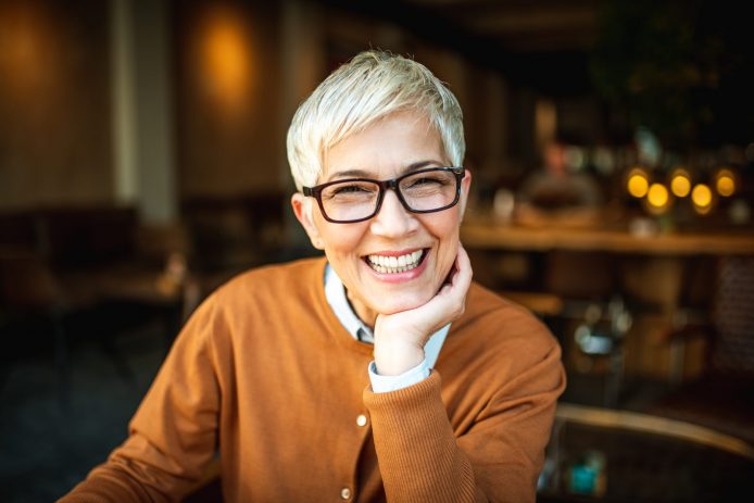 Older woman with perfect smile smiling at a restaurant