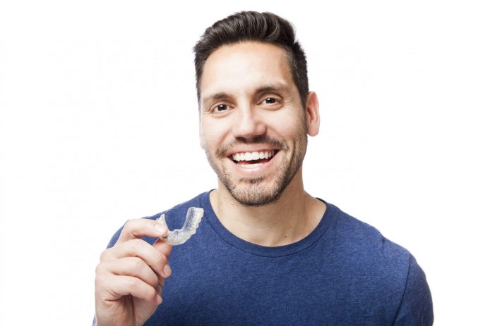 Young man smiling about to put in clear aligners