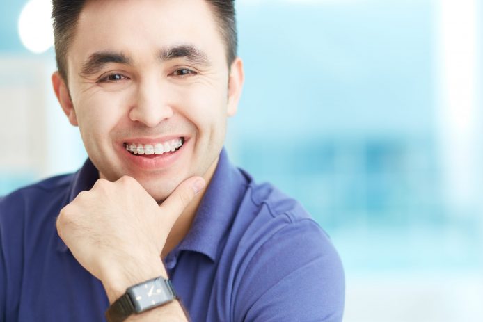 Young man posing and smiling with clear braces