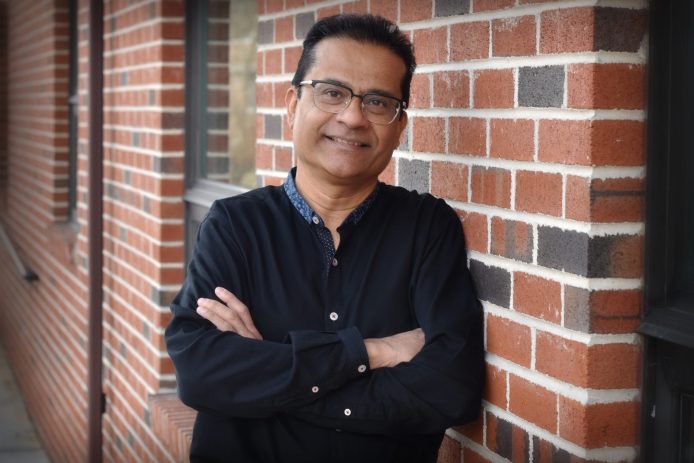 Dr. Sam Ghosh smiling against a brick wall