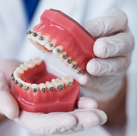 An orthodontist holding a mouth mold with braces