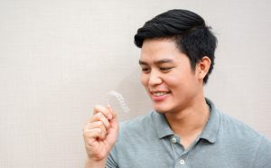 A young man looks at his Invisalign aligner tray