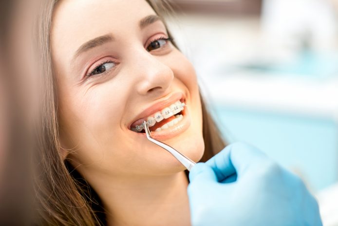 Young woman smiling with braces at an orthodontic appointment